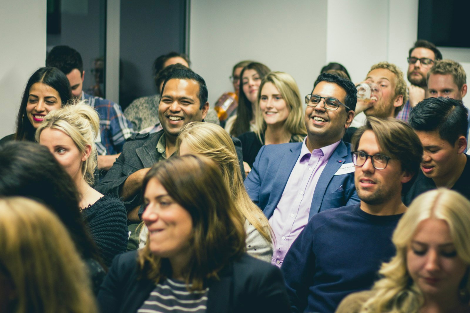 Seated crowd smiling and laughing during a show in a small room