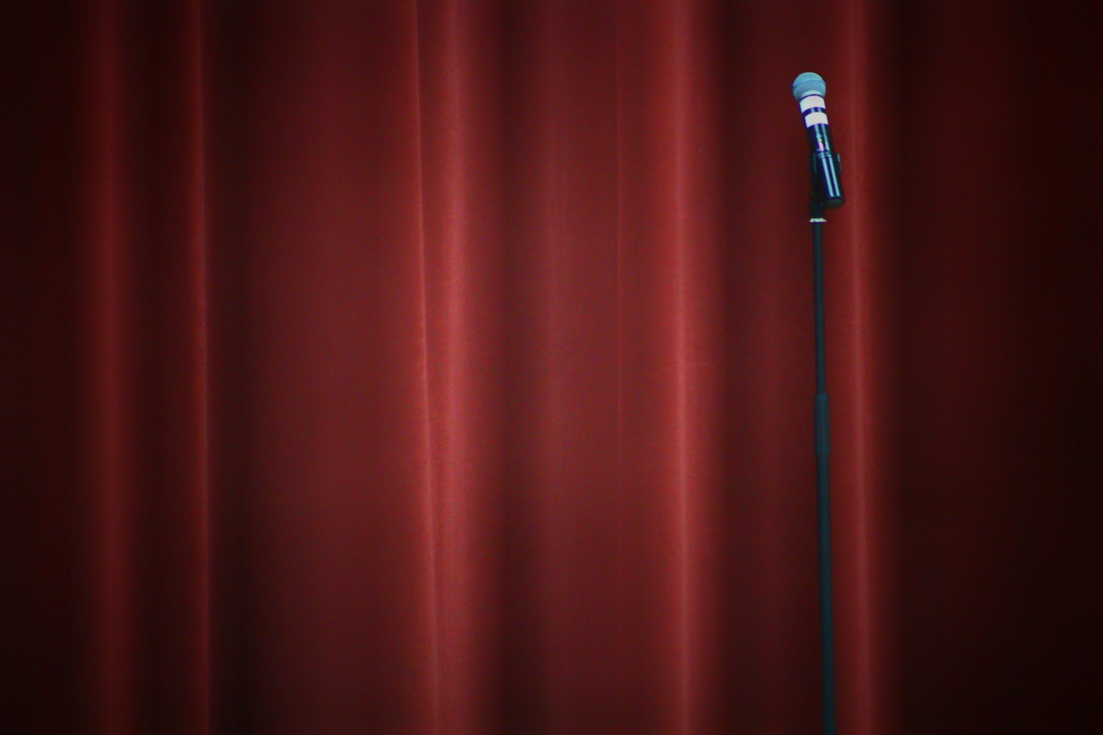 Microphone on a stand in front of a red stage curtain