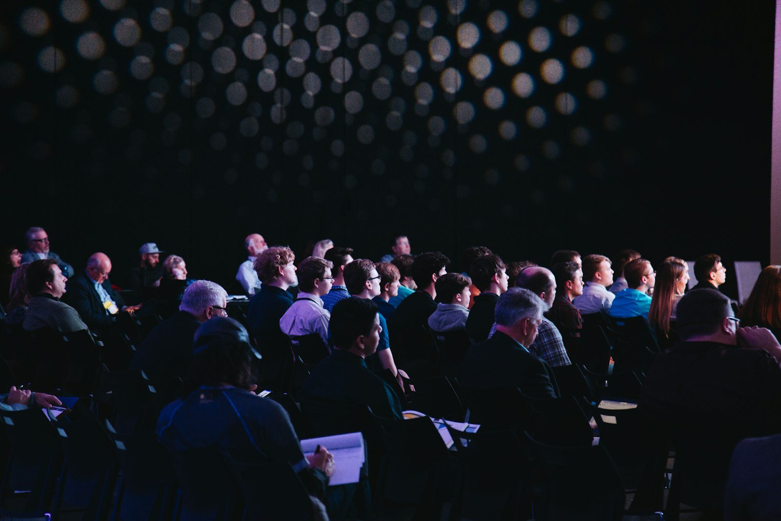 Audience seated in a dark showroom watching a live performance