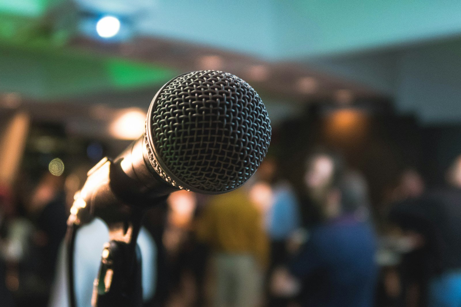Handheld microphone raised above a blurred bar crowd