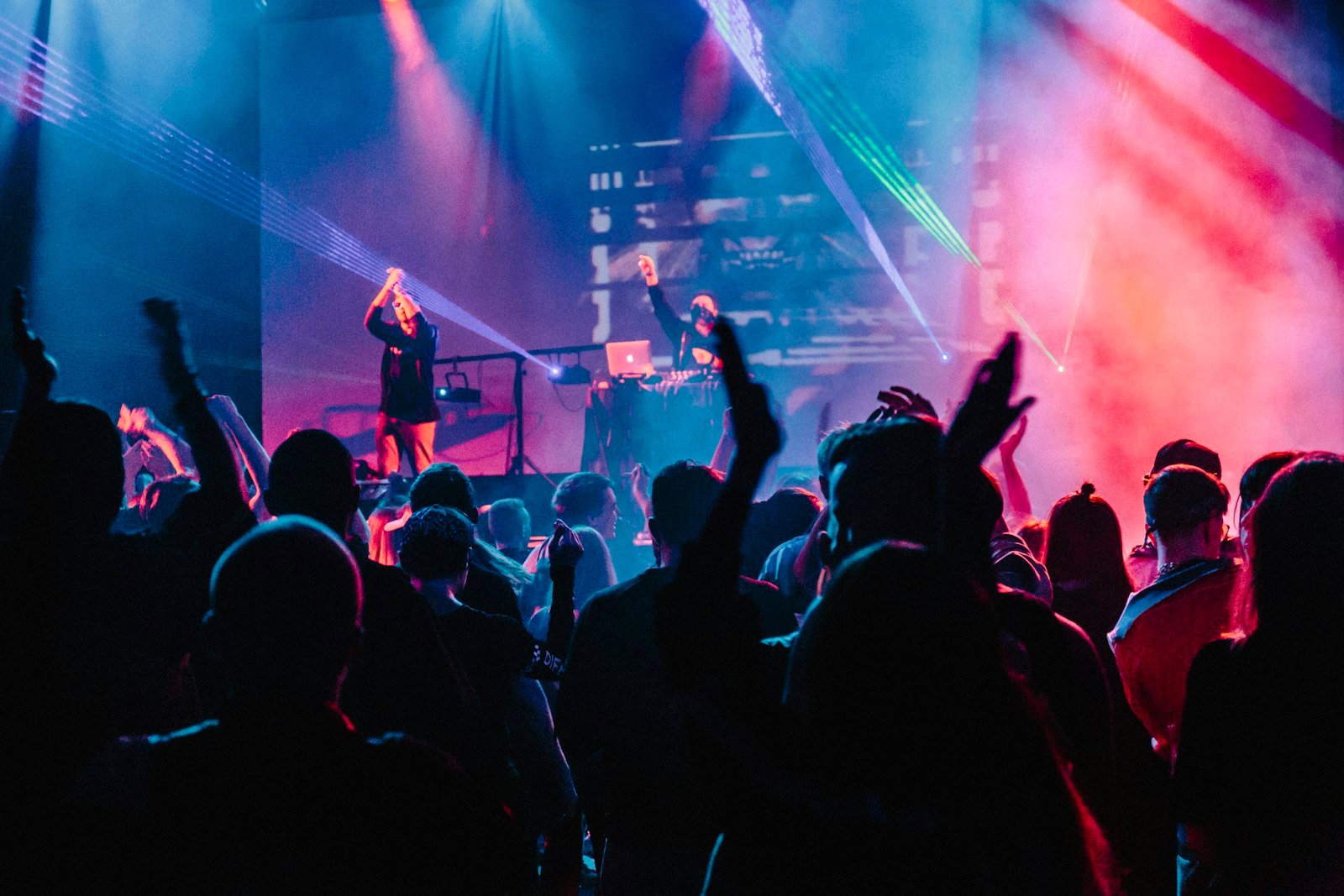 Comedy club stage under colored lights with a crowd raising phones