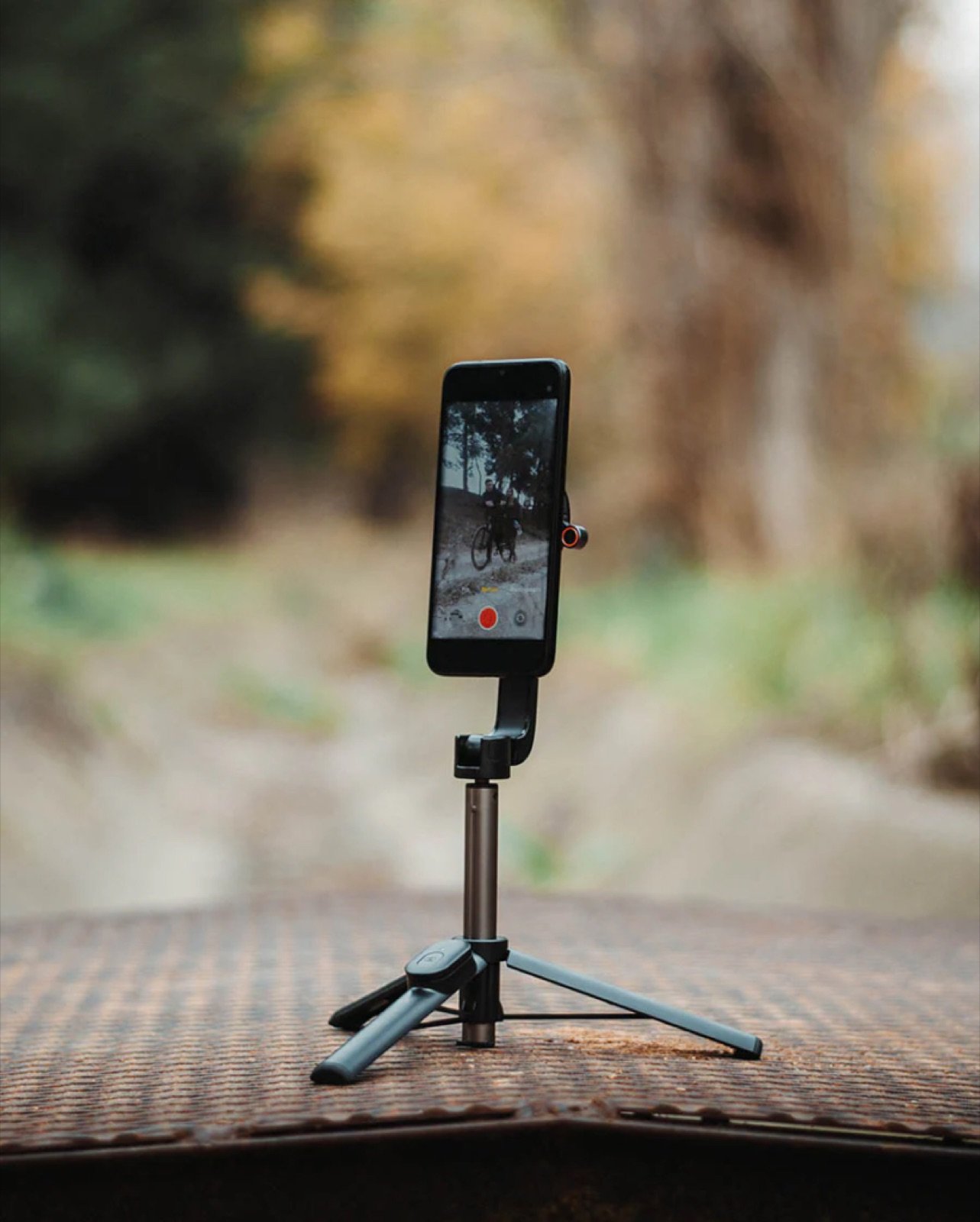 Phone mounted on a small tripod recording video outdoors, showing how a second phone can capture backup audio